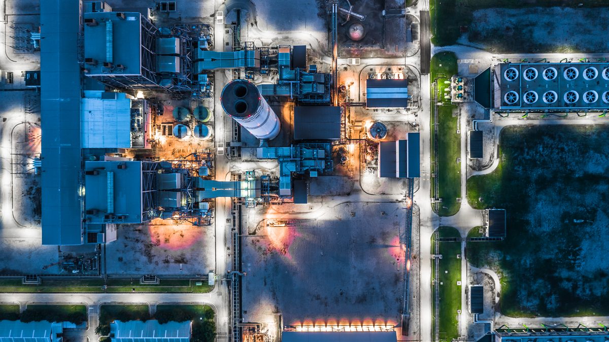صورة جوية توضيحية لمباني ومعدات محطة توليد كهرباء مضاءة عند الغروب